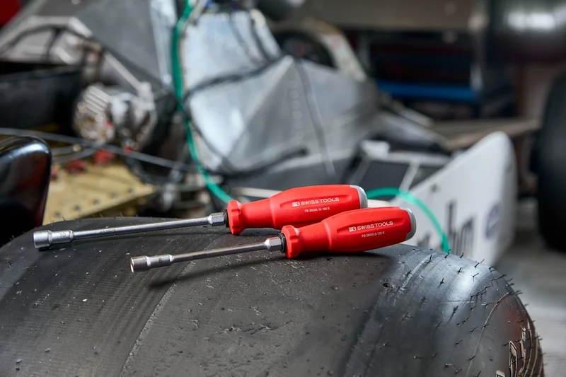Two red screwdrivers resting on a tire.